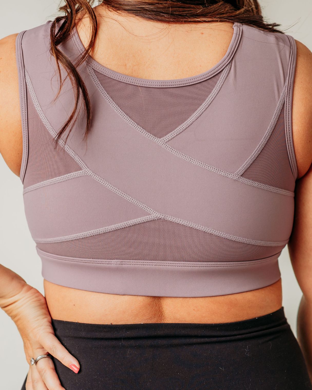 Back view of woman wearing lavender Pipperly Empower posture support sports bra showing the criss-cross design back panel